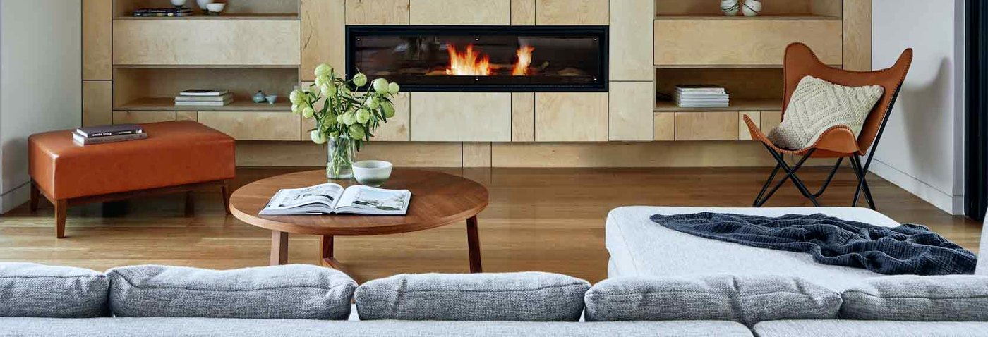 A birch-panelled wall with a long gas fire, open shelves and a leather sling chair