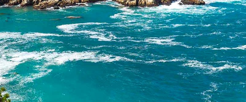 Turquoise water and white surf breaking around granite rocks